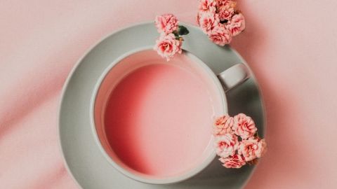 Une tasse avec un liquide rose et des fleurs roses