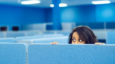 Une femme se cache derrière une paroi dans un grand open-space