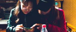 Deux jeunes femmes chinoises regardent un smartphone dans un restaurant