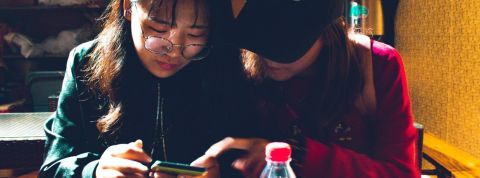 Red Mirror : le livre pour comprendre le quotidien hypertechnologique des Chinois Deux jeunes femmes chinoises regardent un smartphone dans un restaurant