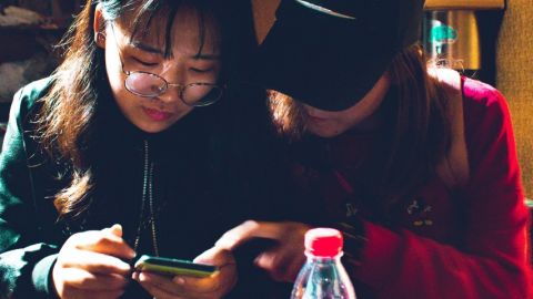 Deux jeunes femmes chinoises regardent un smartphone dans un restaurant
