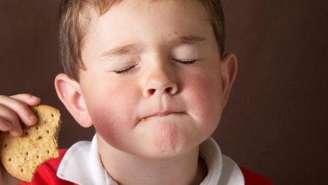 Un petit garçon qui mange un gâteau en fermant les yeux