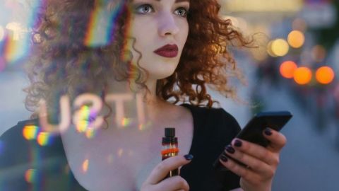 Une femme tenant un smartphone et une cigarette électronique