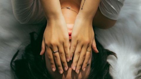 femme sur son lit, mains sur les yeux