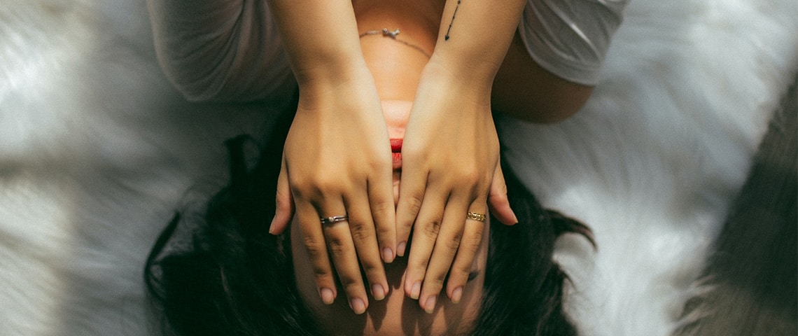 femme sur son lit, mains sur les yeux