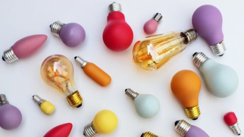 Des ampoules de différentes couleurs éparpillées sur un fond blanc
