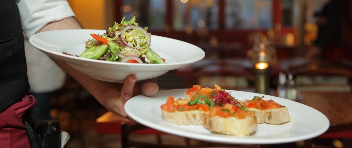 Écotable lance la première plateforme de mesure d’impact environnemental à destination des professionnels de la restauration. Serveur portant 2 plats