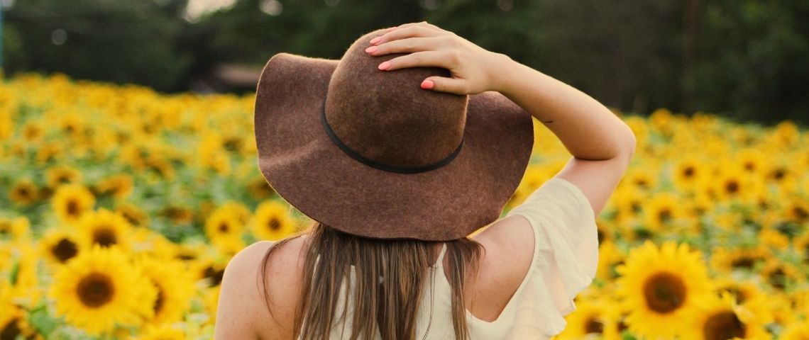 Fondée en 2020 Fairytale est une nouvelle boutique en ligne de mode éthique et écologique pour femme soucieuses du respect de la planète Femme de dos dans un champ de tournesol