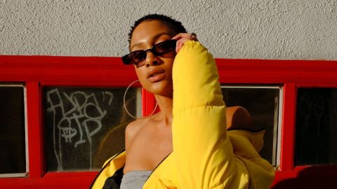 Une femme pose avec des lunettes rectangulaire et une grosse doudoune jaune