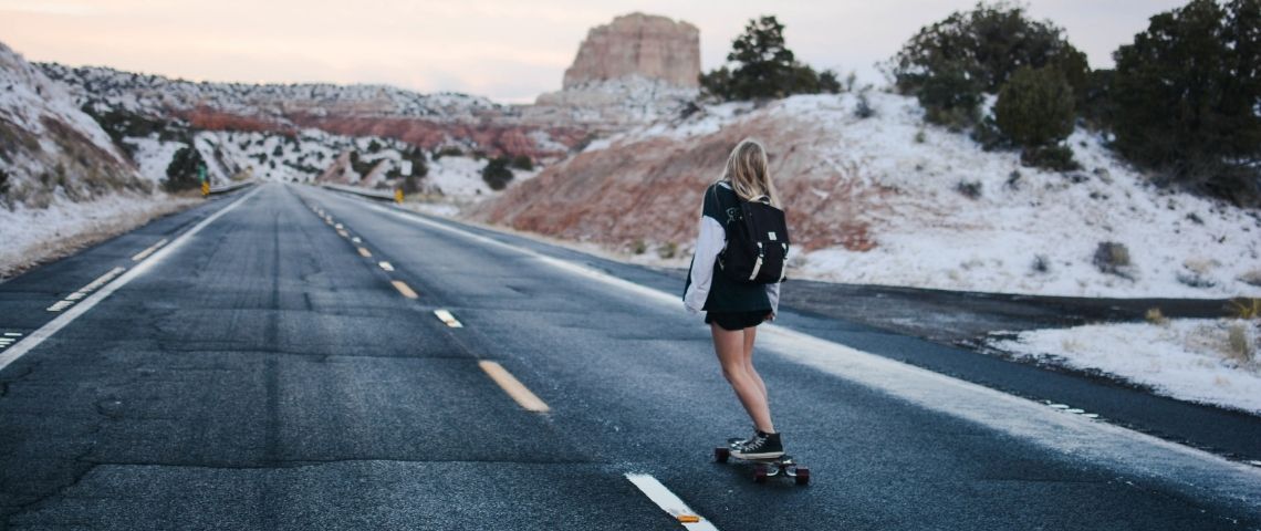 Extrême crée le programme d’Empowerment féminin Extrêmely YOU autour de personnalités passionnées, libres et inspirantes. Jeune femme de dos faisant du skate sur une route