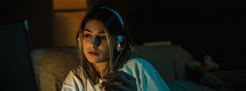 Ça y est, Netflix part à la chasse aux partages de comptes Une jeune femme regarde un film le soir dans son canapé