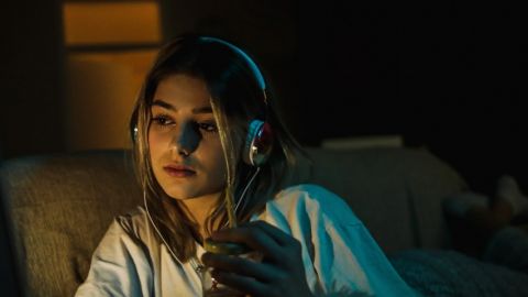 Une jeune femme regarde un film le soir dans son canapé