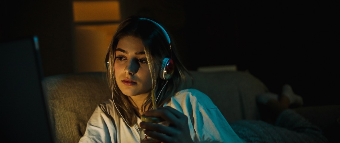 Ça y est, Netflix part à la chasse aux partages de comptes Une jeune femme regarde un film le soir dans son canapé