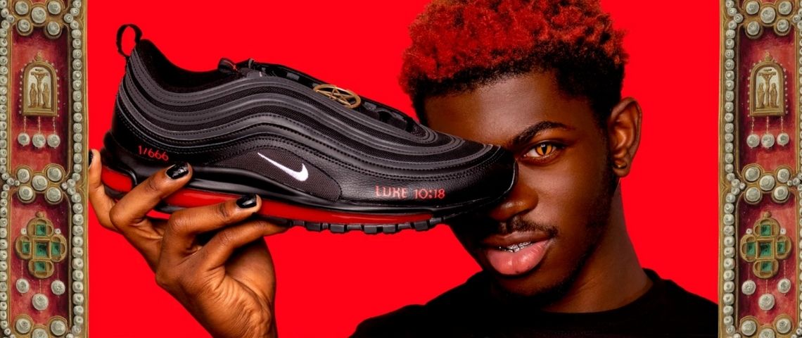 Les Satan Shoes de MSCHF Lil Nas X tenant une chaussure - Satan - de MSCHF