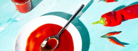 La tendance du piment Une assiette avec une sauce rouge et des piments rouges sur fond bleu