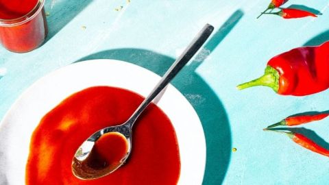 La tendance du piment Une assiette avec une sauce rouge et des piments rouges sur fond bleu