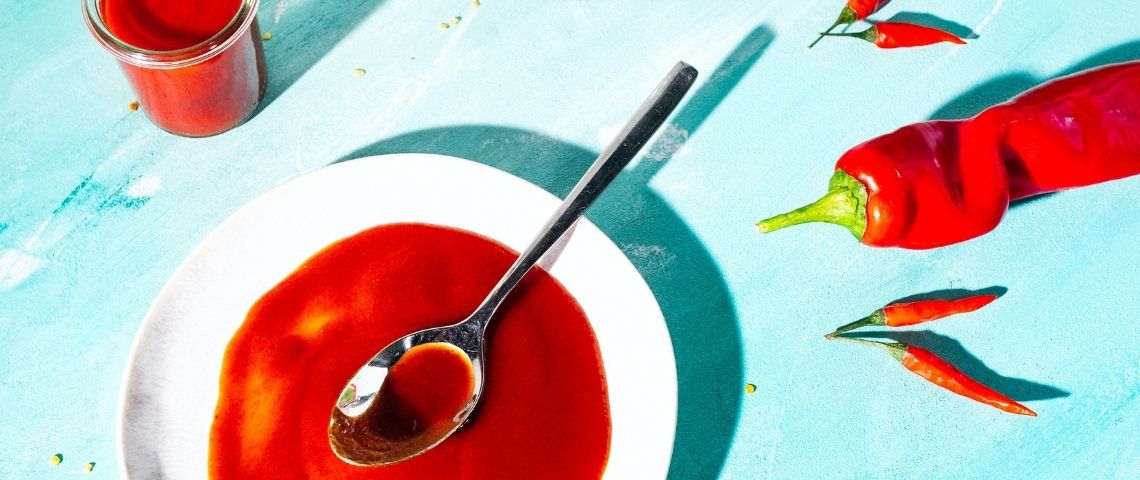 La tendance du piment Une assiette avec une sauce rouge et des piments rouges sur fond bleu