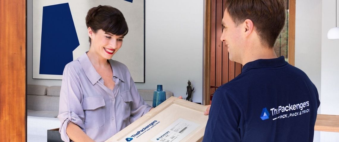 La start-up française, ThePackengers a développé un algorithme et un module uniques au monde au service du transport des objets fragiles Femme recevant un colis, d'un livreur portant un t-shirt avec le le logo ThePackengers