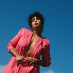 Une jeune femme en tailleur rose devant le ciel