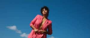 Une jeune femme en tailleur rose devant le ciel