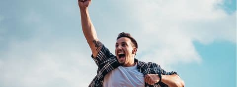 Un homme lève le bras pour célébrer sa joie Pour les entreprises, récompenser ses clients va devenir essentiel