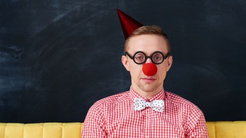 Un homme déguisé en clown à l'air triste sur un canapé jaune