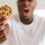 Un homme énervé tenant un cookie dans sa main