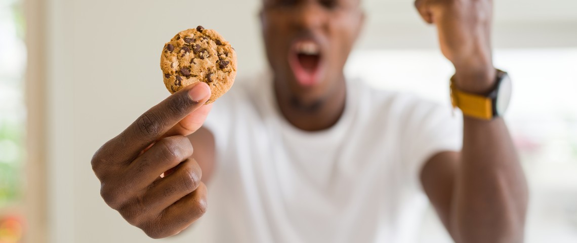 Des cookies ou des euros ? Sur certains sites, il faut désormais choisir Un homme énervé tenant un cookie dans sa main