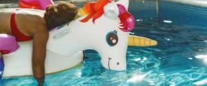 Une personne fatiguée sur une bouée licorne dans une piscine