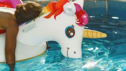 Une personne fatiguée sur une bouée licorne dans une piscine
