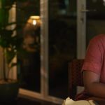 Une femme l'air épuisée travaille sur son ordinateur dans un salon