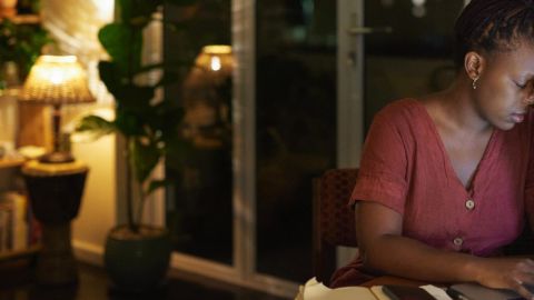 Une femme l'air épuisée travaille sur son ordinateur dans un salon