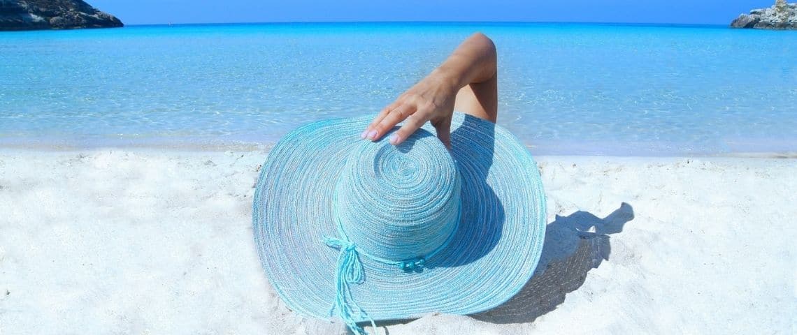 Luko annonce un partenariat avec Airbnb et annonce enrichir son offre d’une option spécifique pour couvrir les logements lorsqu’ils sont occupés par des locataires pour de courte durée. Femme allongée sur la plage, avec le visage caché derrière un chapeau de paille bleu