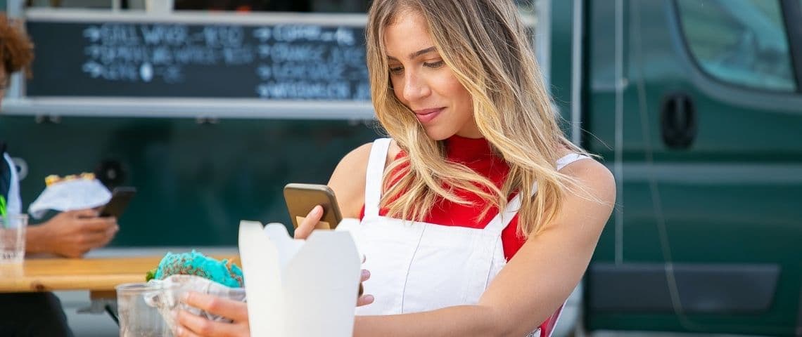 Quelles sont les marques préférées des millennials qui cartonnent sur Instagram ? Une femme en train de prendre son sandwich en photo avec son smartphone