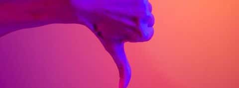 Une main en train de baisser son pouce sur un fond coloré