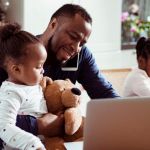 Un papa en train de s'occuper de ses deux petites filles en télétravail