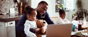 Un papa en train de s'occuper de ses deux petites filles en télétravail