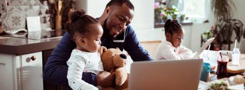 Comment devenir un manager empathique ? Un papa en train de s'occuper de ses deux petites filles en télétravail