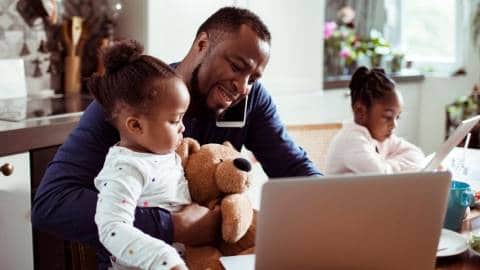 Un papa en train de s'occuper de ses deux petites filles en télétravail