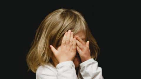Une petite fille se cache le visage avec ses mains