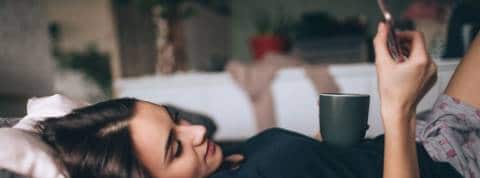 Les tendances lecture en 2021 Une femme qui lit sur son smartphone, allongée