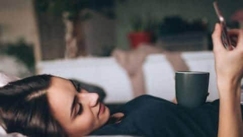 Une femme qui lit sur son smartphone, allongée