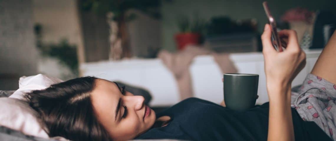 Les tendances lecture en 2021 Une femme qui lit sur son smartphone, allongée