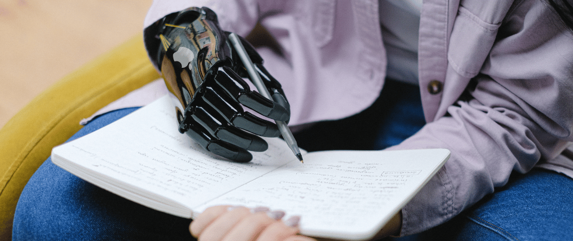 Robotic Hand Writing Homme avec une main bionique écrit sur un carnet au stylo
