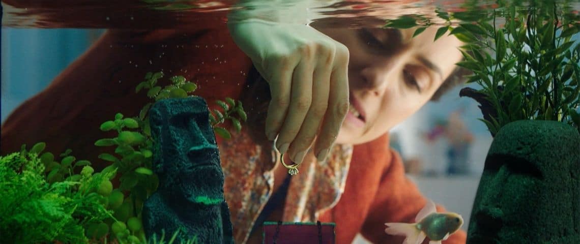 Groupama, accompagné par l'agence Marcel, communique sur son offre de télésurveillance à domicile Femme mettant une bague dans un petit coffre fort dans un aquarium