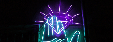 Le luxe made in laboratoire Une main bleue en néon tient un diamant violet aussi en néon