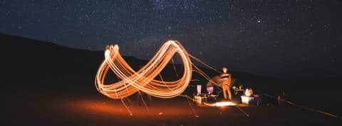 Qui est Dfinity, la start-up qui veut repousser les limites d'internet ? Un sigle infini dessiné en lumière par des personnes dans le désert