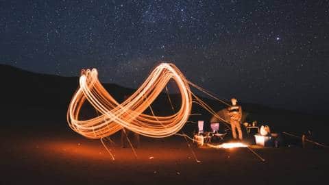 Un sigle infini dessiné en lumière par des personnes dans le désert
