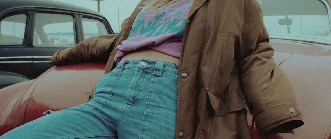Z contre Y : tout se joue autour du jean! Une fille en jean appuyée contre une voiture rouge