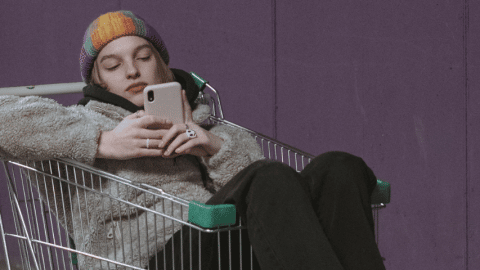 Une jeune femme assise dans un chariot tient son téléphone portable